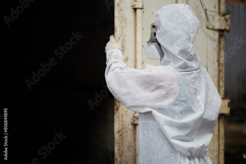 back view worker wearing PPE protective clothing with gas masks and checking inside container in the factory