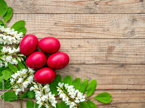 red easter eggs framed by acacia flowers and leaves