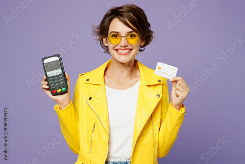 Young woman she wear yellow shirt white t-shirt casual clothes glasses hold wireless modern bank payment terminal to process acquire credit card isolated on plain purple background. Lifestyle concept © ViDi Studio