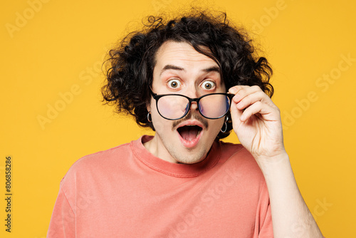 Close up young fun cool shocked surprised happy man he wear pink t-shirt casual clothes touch lower glasses look camera isolated on plain yellow orange background studio portrait. Lifestyle concept. photo