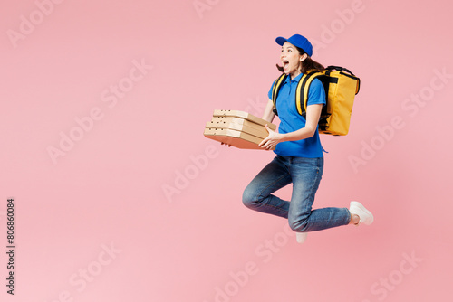 Full body side view fun delivery woman wearing blue cap t-shirt uniform thermal bag work as dealer courier hold pizza in paper blank craft flatbox isolated on plain pink background. Service concept. photo