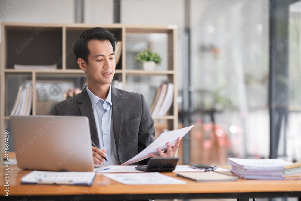 Young Asian businessman working using laptop in modern office, analyzing accounts Financial investment information report Young Asian businessman working using laptop in modern office, analyzing accounts Financial investment information report