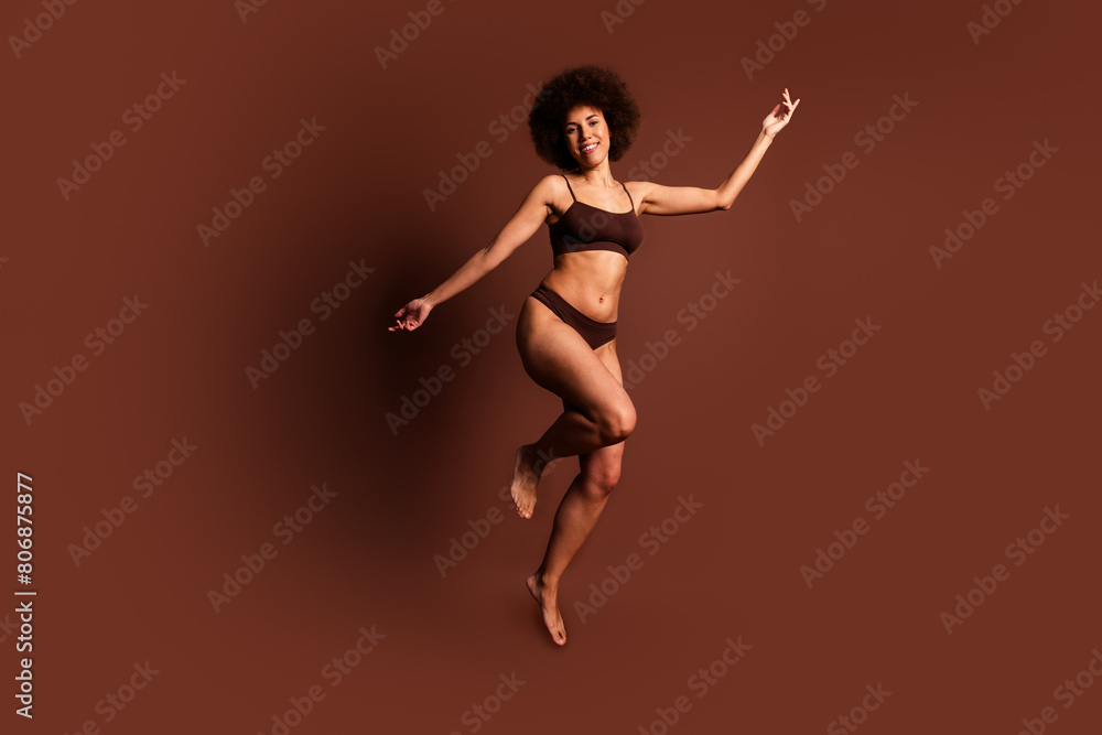 Full length photo of excited funny lady underwear jumping enjoying women rights isolated brown color background