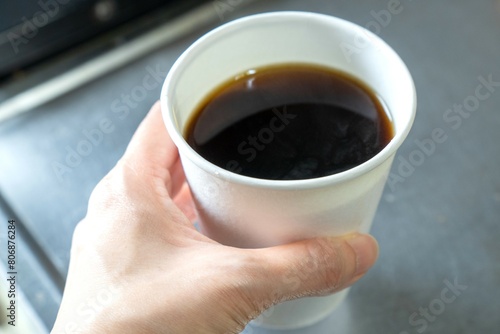 紙コップに注いだコーヒーを持つ人の手元