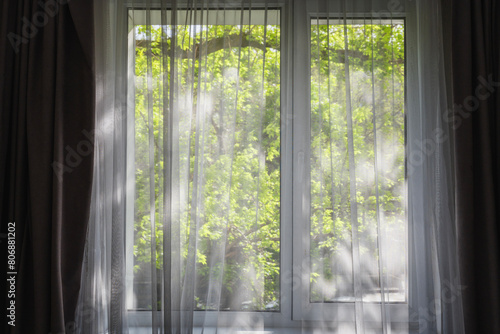 Transparent white curtain with window view with tree garden background.