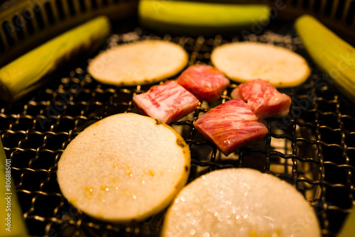  a grill where freshly prepared meat slices and vegetables are being cooked