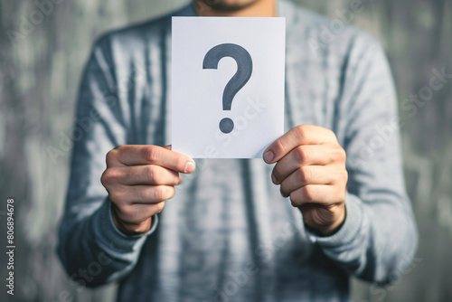 Man holding a question mark sign closeup in gray sweater