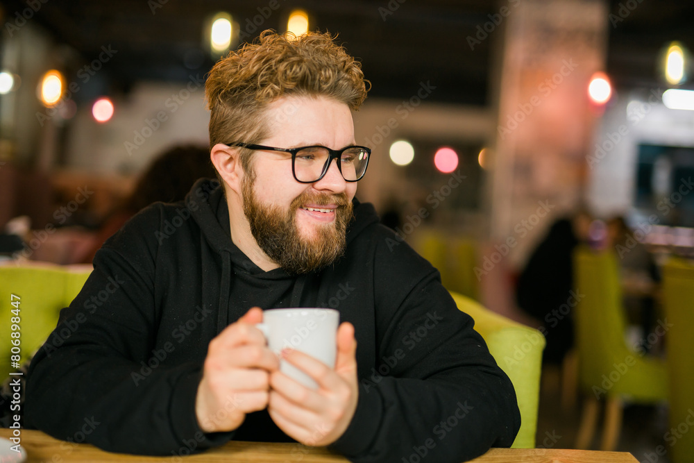 Bearded curly man smiling confident drinking coffee in restaurant or coffee shop. Millennial generation and Gen Y