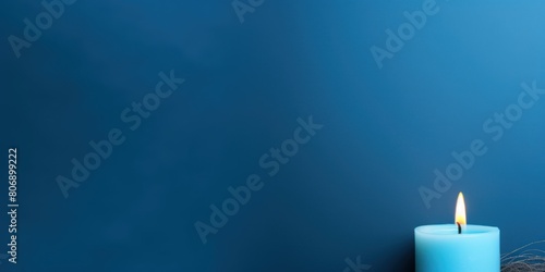 Blue background with white thin wax candle with a small lit flame for funeral grief death dead sad emotion with copy space texture for display 