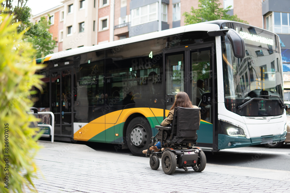 Disability collection. Woman in electric wheelchair in front of an inaccessible bus for people with reduced mobility.