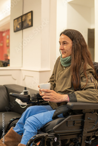 woman brown hair in electric wheelchair has a coffee in a tea room. Confident, confident and happy. motor disability concept