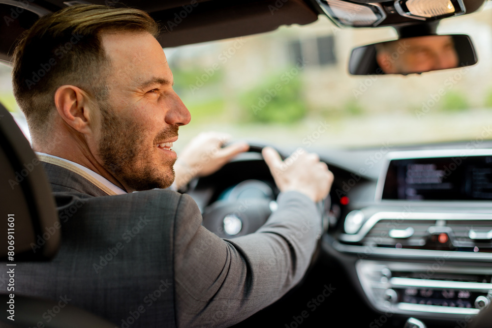 Smiling man enjoying a sunny drive in a modern car interior Smiling man enjoying a sunny drive in a modern car interior