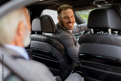 Smiling passenger engaging in friendly conversation with driver inside a modern car © BGStock72