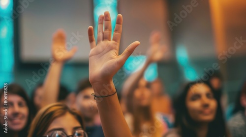 Close-up of a student's hand raising their hand to answer a question in a classroom setting, with the teacher smiling and nodding in response. photo