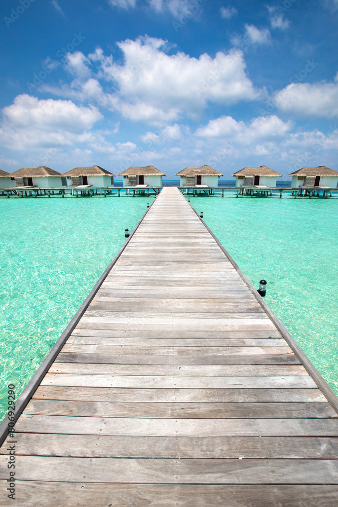 paradise beach destination in Maldives, wooden pier in hotel with luxury houses for tourists