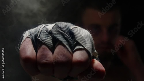 mma fighter punches the camera in the dark backlit. anamorphic effect. shadow fight