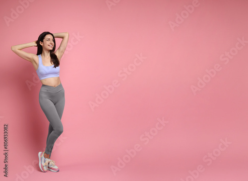 Happy young woman with slim body posing on pink background