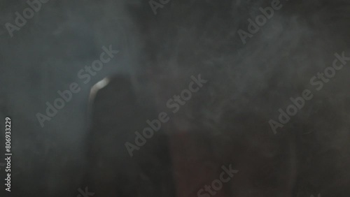 punching the camera. close-up of a bandaged fist punching out of the darkness through the smoke into the camera. photo