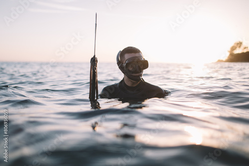 Young active man in water holds a speargun photo