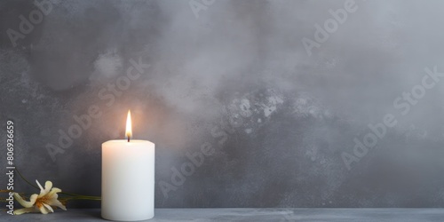 Gray background with white thin wax candle with a small lit flame for funeral grief death dead sad emotion with copy space texture for display  photo