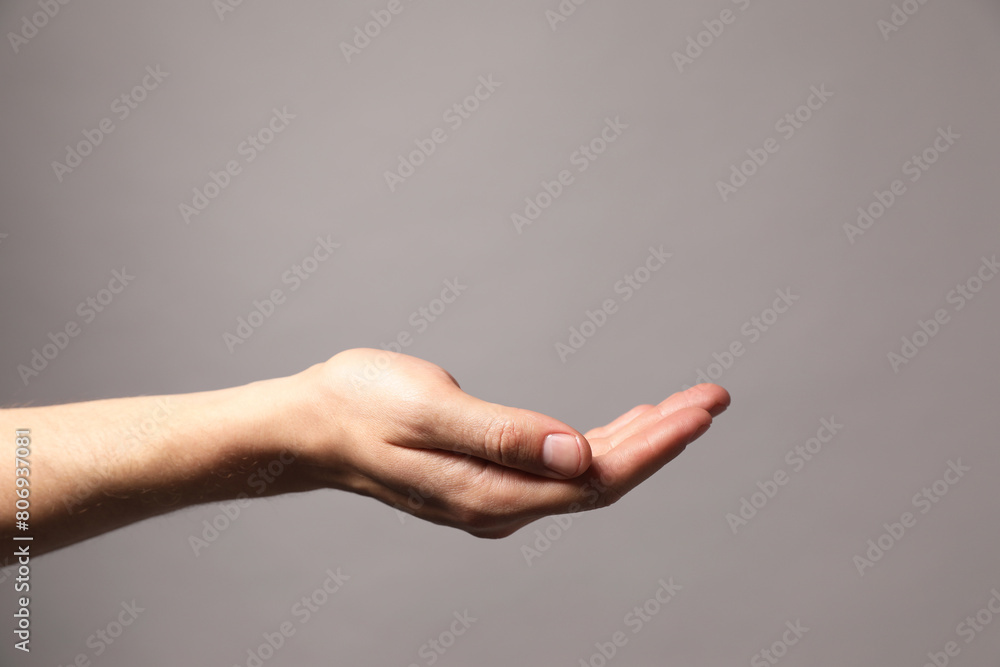 Man holding something in hand on grey background, closeup. Space for text Man holding something in hand on grey background, closeup. Space for text