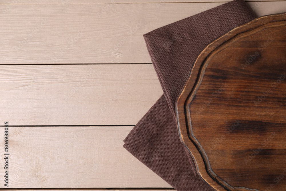 Cutting board and napkin on beige wooden table, top view. Space for text Cutting board and napkin on beige wooden table, top view. Space for text