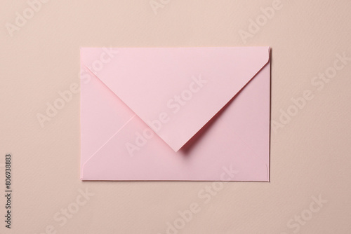 Letter envelope on beige background, top view