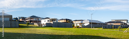 Panoramic view of a large vacant land lot with some residential suburban houses in the background. Panorama of Australian homes in a neighbourhood. Real estate  housing. San Remo VIC Australia