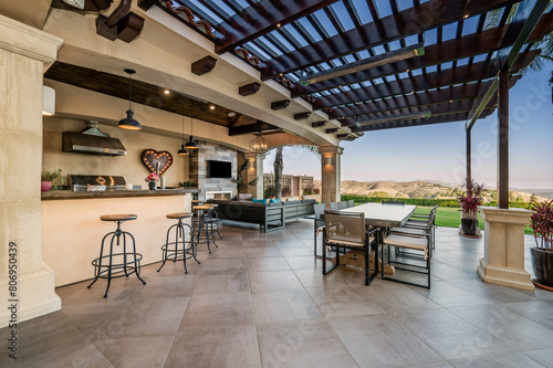 Canvastavla an outdoor kitchen with a large bar and two tables on the porch