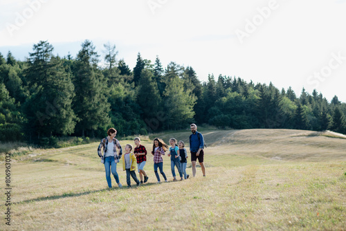 Young students walking across meadow during biology field teaching class, holding hands. Dedicated teachers during outdoor active education teaching about ecosystem, ecology. © Halfpoint