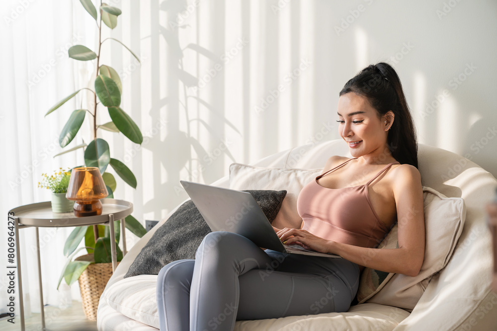 Asian beautiful lady with black long hair work at the notebook sit down on the sofa at home . Check on oline shops for sales - technology woman concept for alternative office freelance Asian beautiful lady with black long hair work at the notebook sit down on the sofa at home . Check on oline shops for sales - technology woman concept for alternative office freelance