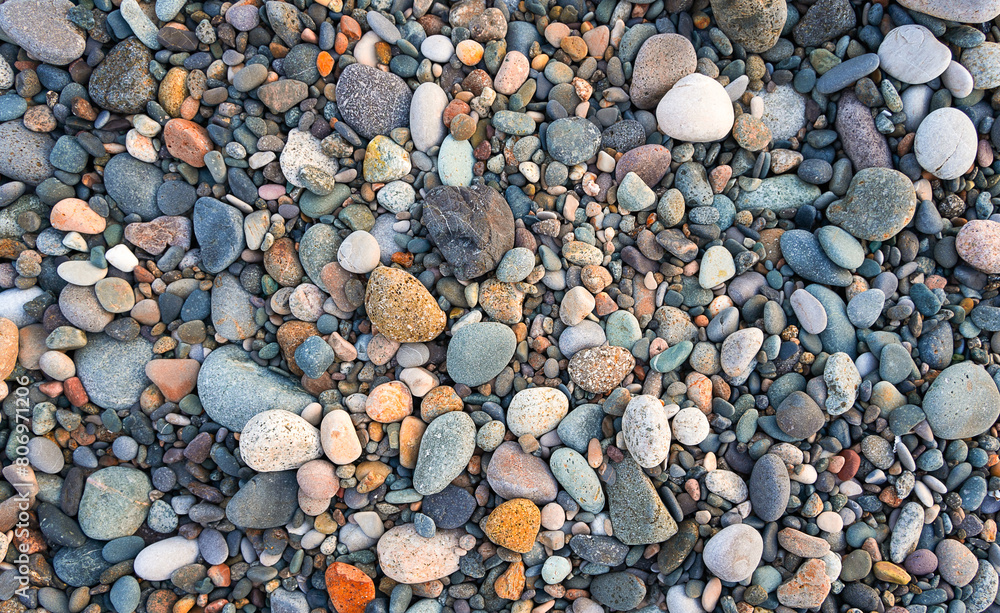 Multi-colored pebbles on a pebble beach, top view Multi-colored pebbles on a pebble beach, top view