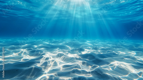 Underwater view with bright sunlight streaming through blue water onto a sandy bottom. photo