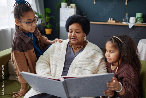 Cuadro en lienzo Portrait of senior Black woman with two children looking at photo album together