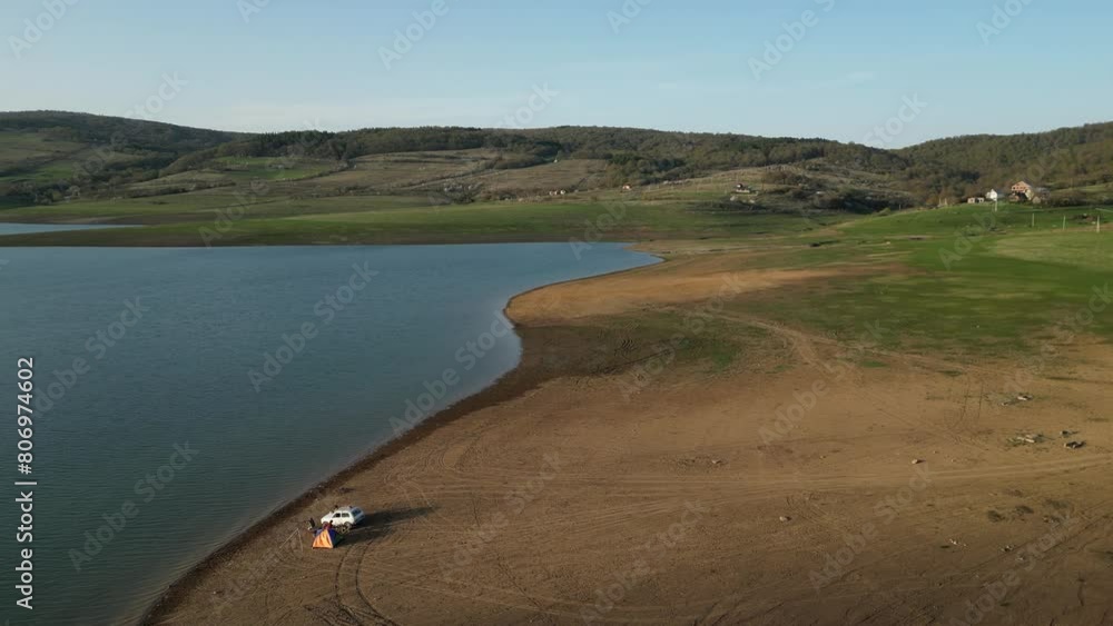 car and tent on the shore of a lake in the mountains, golden hour, aerial view car and tent on the shore of a lake in the mountains, golden hour, aerial view