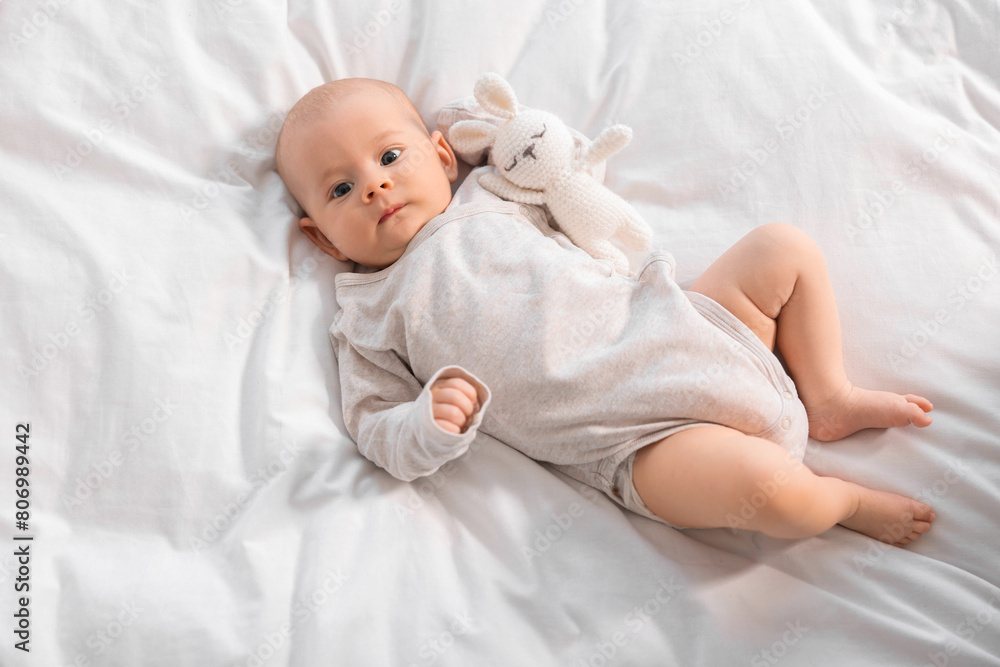 Cute little baby with toy lying on white sheets, top view Cute little baby with toy lying on white sheets, top view