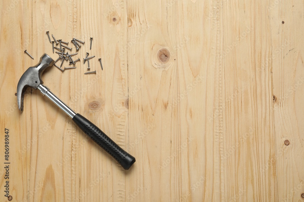 New hammer and metal nails on wooden table, flat lay. Space for text