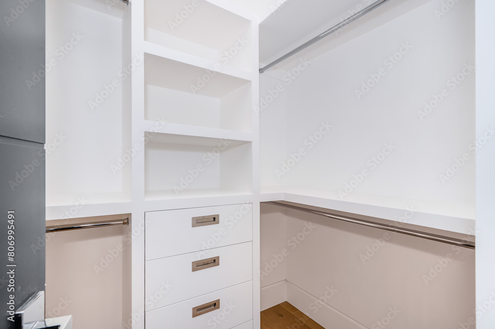 Fototapeta premium a walk in closet with wooden floors and white walls is shown