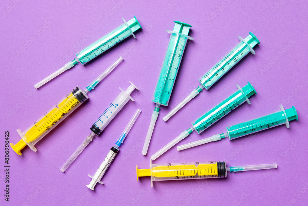 Top view of medical syringes with needles at purple background with copy space. Injection treatment concept Top view of medical syringes with needles at purple background with copy space. Injection treatment concept