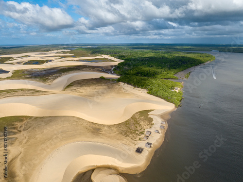 Aerial view of Parque da Dunas - Ilha das Canarias, Brazil. Huts on the Delta do Parnaíba and Delta das Americas. Lush nature and sand dunes. Boats on the river bank
