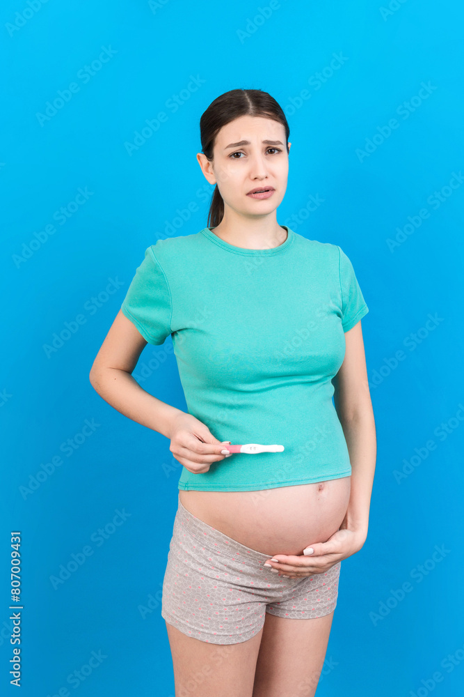 positive pregnancy test with two stripes against happy pregnant woman abdomen at Colored background. Future mother in gray dress. Pregnancy surprise. Copy space positive pregnancy test with two stripes against happy pregnant woman abdomen at Colored background. Future mother in gray dress. Pregnancy surprise. Copy space