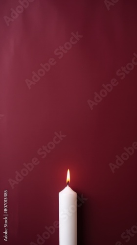 Maroon background with white thin wax candle with a small lit flame for funeral grief death dead sad emotion with copy space texture for display 