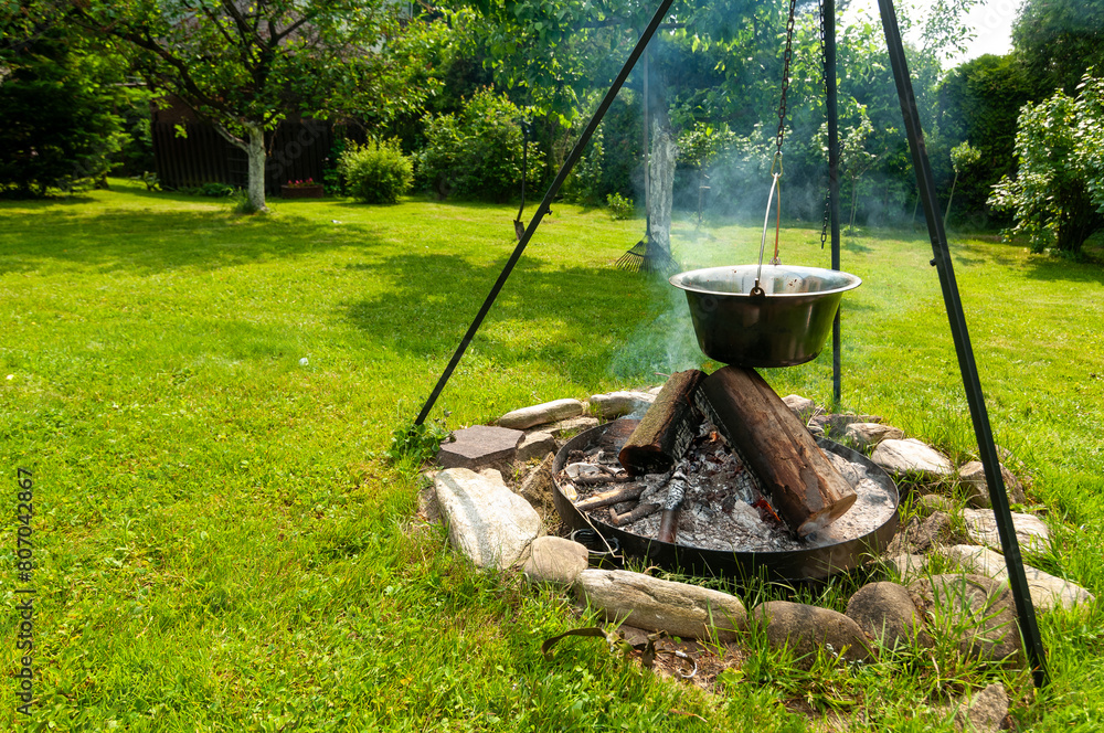 Fototapeta premium Kociołek z jedzeniem gotowanym na ognisku w ogrodzie