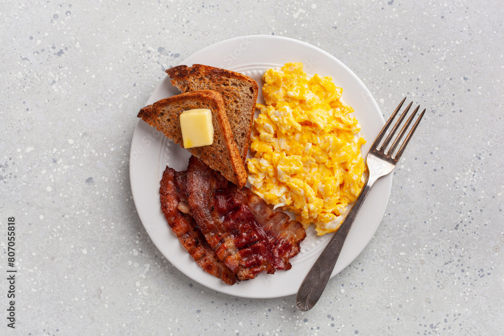 traditional scrambled egg breakfast with bacon and toast