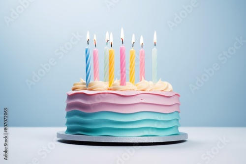 blue birthday cake with colorful candles on a blue background  with a pastel color palette 