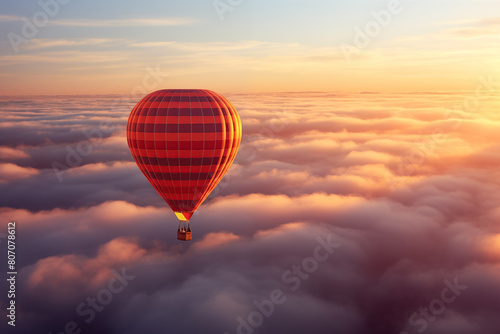 Colorful hot air balloon floats over a sea of clouds at sunset © Dmitry Rukhlenko