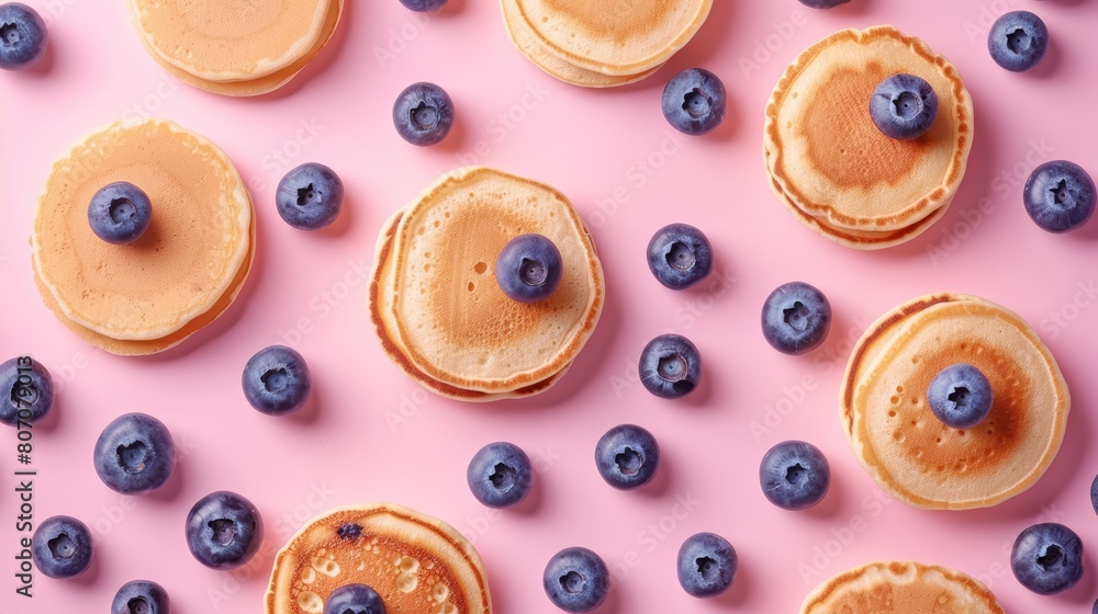 Fototapeta premium Sophisticated top view portrait of pancakes and blueberries displayed in a flawless geometric arrangement on a gently transitioning soft pink background