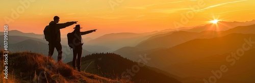 silhouettes of a couple pointing at a sunset in mountains, a panoramic view with for a travel and adventure concept