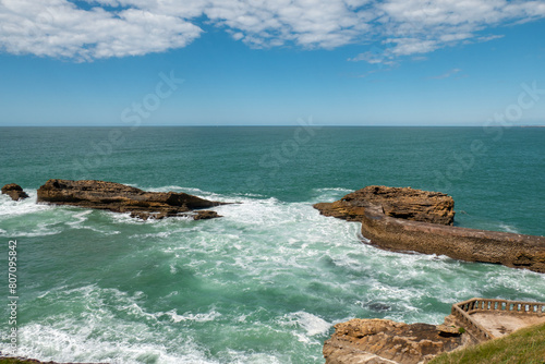 Alguns rochedos no mar com um pequeno miradouro para apreciação da bonita paisagem em Biarritz, no País Basco francês