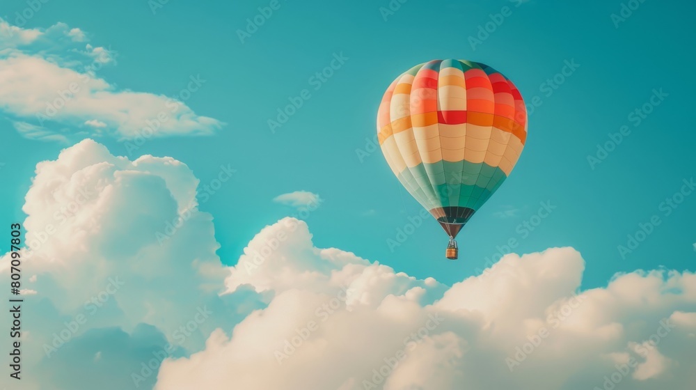 Fototapeta premium A rainbow-colored hot air balloon floating gracefully against a backdrop of fluffy white clouds, creating a picturesque scene in the sky.